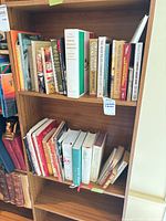 Two shelves filled with cookbooks on wooden bookshelf