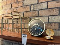 Magazine rack, clock, candle holder grouped on shelf