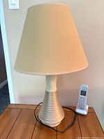 Full view of lamp on table, showing base, shade, cord