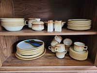 Stoneware plates, bowls, salt & pepper, creamer, sugar bowl on shelf