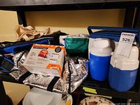 Shelf with coolers, jugs, lantern box and bags