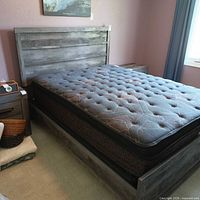 Full view of queen bed frame with headboard and side table for scale