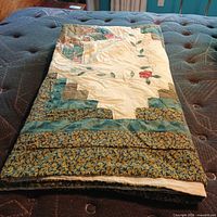Folded quilt showing layered patchwork border and off-white backing