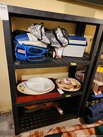 Full view of black plastic shelving unit with four shelves; contents not included