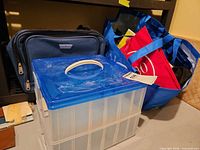 Storage box, blue reusable bag with totes, navy briefcase visible