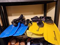 Blue flippers, yellow flippers, water boots on shelf