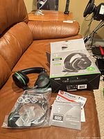 Headset, cable in plastic, manual, and box displayed on couch
