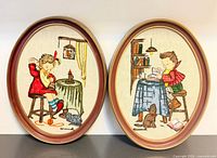 Front view of both oval framed embroideries