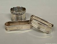 Three napkin rings grouped; shows overall forms, engraving V.I.E. and Sterling mark on one rectangular ring