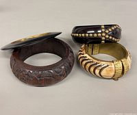Group shot of three bangles detailing carving, studs, faux ivory and metal accents