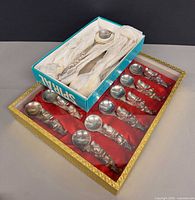 Boxed spoons on red fabric and separate rests box visible