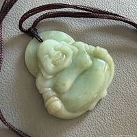 Front view of carved jade laughing Buddha pendant on cord