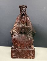 Front view of carved stone figure showing facial detail, robes and pedestal