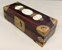 Angled view of closed wooden jewelry box with brass fittings and jade inlay