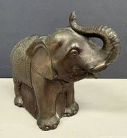 Left-front view of metal elephant coin bank showing trunk and facial details
