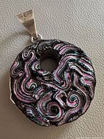Front view showing iridescent swirl design, bail and overall form
