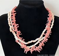 Front view of three-strand pink coral and white bead necklace on display bust