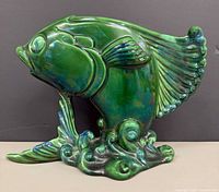 Left-side view of green glazed ceramic koi fish planter showing wave base and tail detail