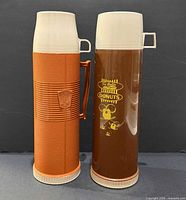 Front view of both thermoses showing logos, textures, lids and bases