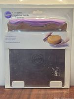 Front view of sealed Wilton cake lifter showing stainless blade and purple handle