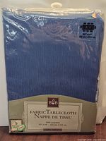 Front of sealed package showing blue tablecloth, brand logo, material, size 60" × 84"
