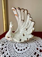 Front view of ceramic swan vase showing raised wings, white glaze and gold accents