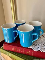 Front view of all four turquoise mugs showing glaze and shape