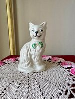 Front view of white Belleek ceramic cat figurine with shamrock bow