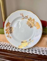Front view of white bone china plate with three gold rose motifs and gilt rim