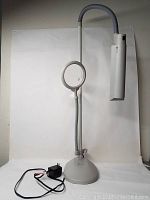 Full view of the OttLite floor lamp with magnifying glass and power cord laid out in front.