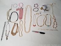 Overview of all jewelry items spread out showing necklaces, bracelets, earrings, and a marker for scale.