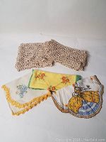 Lot of vintage table linen pieces including several embroidered and tatted runners and an embroidered handkerchief.