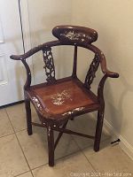Wood corner chair with carved bird and floral supports, floral inlays on seat and backrest. Shows the full chair including the curved armrests and inlaid designs on seat and backrest.