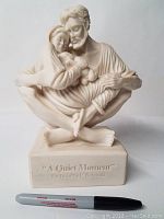 Front view of the sculpture showing the seated man holding woman and child, with engraving on base 'A Quiet Moment By Timothy P. Schmalz'