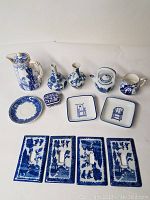 Blue and white china lot with 4 Blue Willow single switch plates, 2 small dishes with blue chair designs, 2 lidded pitchers, 2 bud vases, creamer, and small saucer dish.