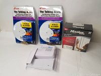 Four items in their original packaging: two Kidde Talking Alarms, one Zenith Doorbell Extender, and one Master Lock SmartTouch garage door opener.