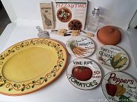 Full lot display with all items: hand-painted serving platter, vegetable plates, capped glass bottle, truffle slicer, pizza stone set, terra cotta garlic dish, garlic spreaders, and garlic oil dish.