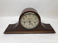 Front view of the wooden Seth Thomas mantel clock showing the rounded glass dial with black Arabic numerals and two winding holes.