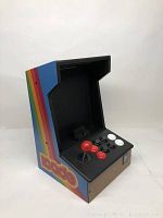 Side-front view of the ION iCade arcade cabinet showing joystick, buttons, side rainbow stripe graphics, and iPad holder inside cabinet.