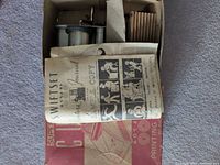 Open box showing Swiftset sample copy sheet covering metal cylinders and accessories