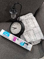 Curtains, clock with lamp, and boxed Minky clothesline displayed on grey upholstery