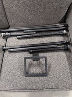 two adjustable black shower curtain rods and one black toilet tissue holder displayed on chair