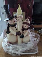 Front view of resin snowman candle showing figures, candle, bulb and condition