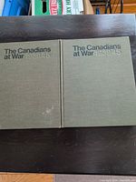Two green hardcover copies of The Canadians at War 1939-1945 on table