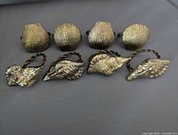 Eight brass shell napkin rings displayed, showing scallop and conch styles