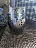 Full front view of chrome ceramic stool showing barrel shape and side cutouts