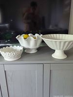 Three white ceramic bowls on cabinet showing relative sizes and styles