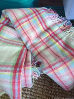 Full view of folded pastel plaid wool blanket with fringe