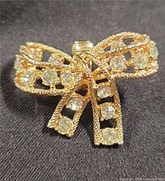 Front view of gold-tone bow earring with clear rhinestones