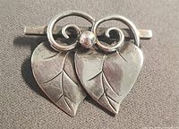 Front view of sterling silver double leaf brooch showing leaves, tendrils, bead and bar